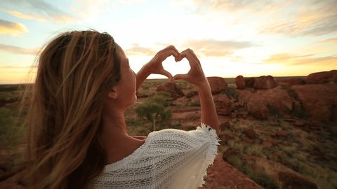 Young woman makes heart shape finger frame to spectacular landscape-sunrise
Young woman at the devil's Marbles makes a heart shape finger frame to the spectacular landscape at sunrise.