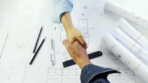 Close-up of architect and engineer shaking hand over blueprint. Concept building team working on project. Cooperation