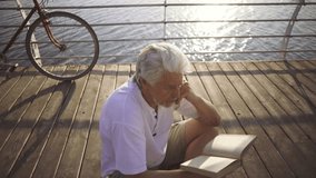 senior man reading book sea at sea front, slow motion - Powered by Shutterstock - Get 15% off with code: PIKWIZARD15