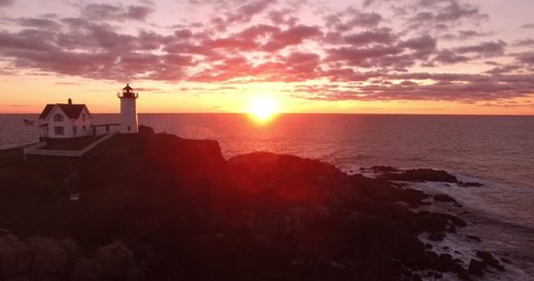 Warm Sunrise with Lighthouse in Silhouette on Rocky Point - Aerial Footage of Cape Neddick Lighthouse, Maine, USA