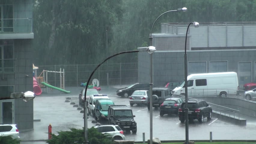 Heavy rain in the city. A very heavy downpour floods the cars in the parking lot next to the house. HD 1920x1080 Video Clip