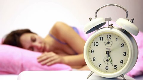 Beautiful woman sleeping soundly and the alarm clock awakens in time