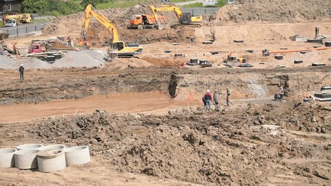 MOSCOW, RUSSIA - JULY 07, 2017: Foremen decide problems of construction. Construction of foundation on large building site outdoors. A lot of builders work on construction site in summery day
