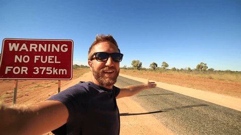 No Fuel warning sign selfie.
Young man in the Australian outback takes a selfie portrait in front of a 'No Fuel' warning sign. Adventure selfie 