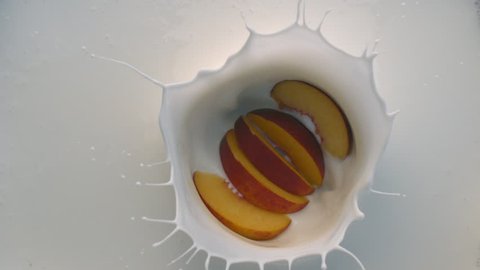 Slices of Peach Fruit Falling into White Yogurt with Splashes