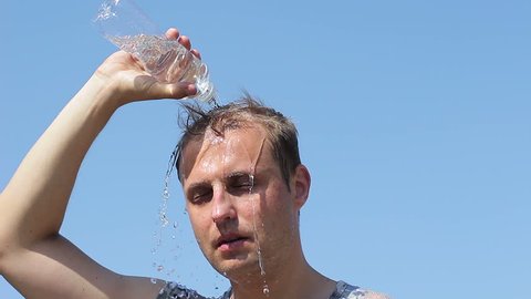 The guy pours water on his head trying to cool. Summer Heat
