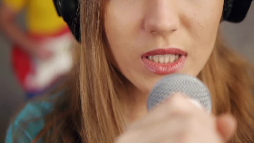 Close-up of female singing and recording song in studio