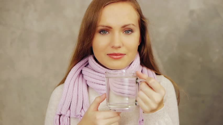 Young sick woman puts aspirin in cup of water