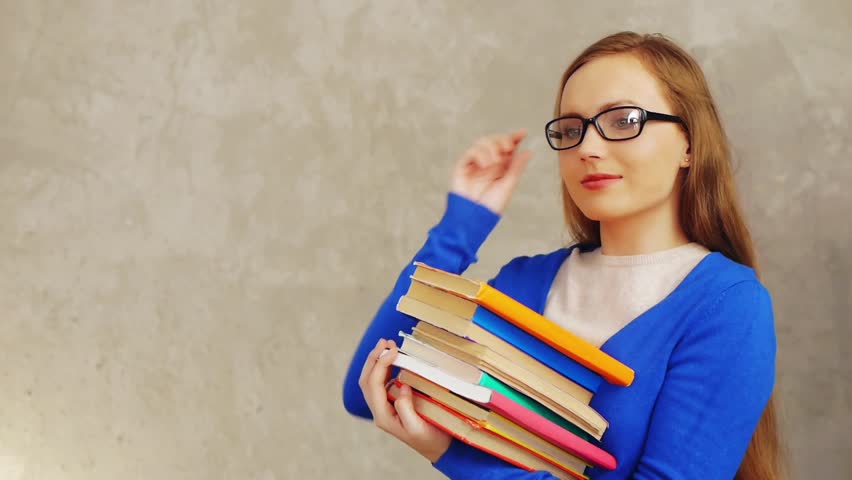 Smart stressful student in glasses holding books