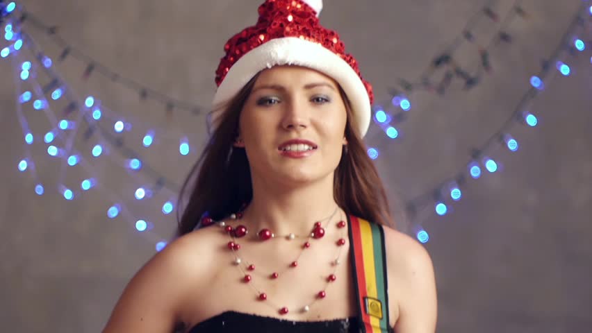 Beautiful woman in Christmas hatplaying on guitar