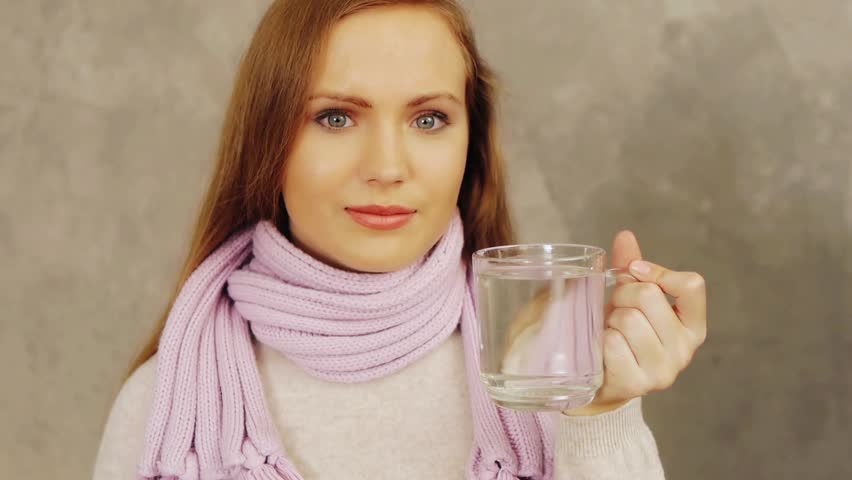 Young ill woman putting aspirin in cup of water