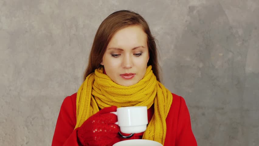 Pretty woman in red coat drinking tea