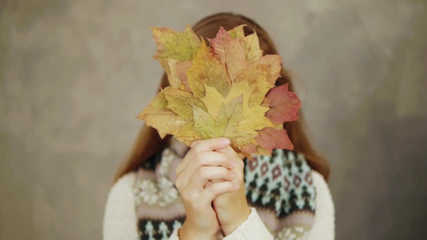 Young woman holding leaves instead her face