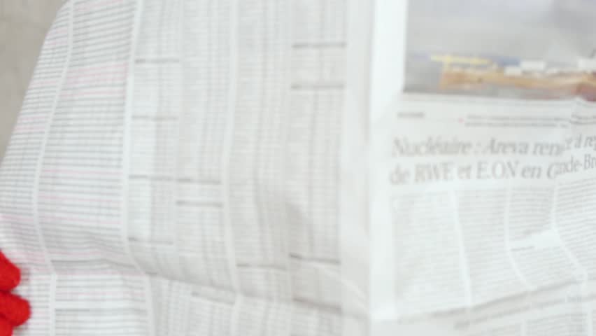 Elegant woman in glasses reading newspaper