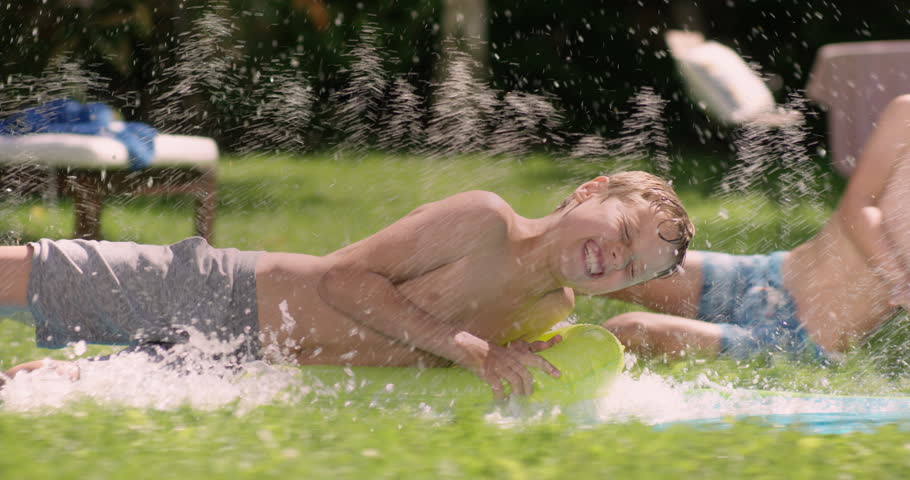 Waterslide fun in the graden. Young Boy is sliding with full speed