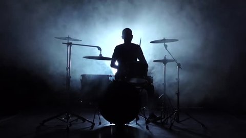 Energetic music in the performance of a professional drummer. Black background. Silhouette. Slow motion