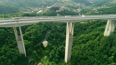 Aerial: Flying over Highway bridge / viaduct road .  Intensive cargo truck traffic in Europe. Logistics  vehicles passing the massive bridge  in the  Alps. Italy 4k
