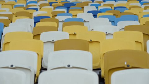 Rows of seats in the stadium. Close up. Background. Empty yellow, white and blue seats without people. Spectator Tribune