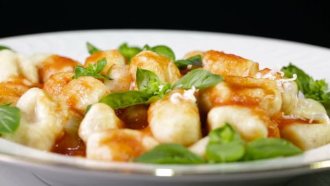 Italian food potato gnocchi in a white dish for a restaurant with grated cheese falling down.