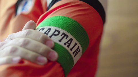 Captain puts armband on sleeve. Sports captain wears his armband with pride ahead of match, preparation before big game.