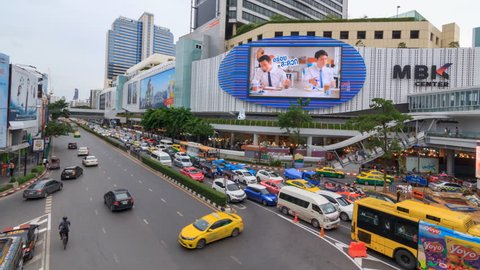 Bangkok , Thailand - 7 August, 2017: Day to night time lapse of at  MBK shopping mall with blur light of traffic / Blur moving lighting of traffic at the road
