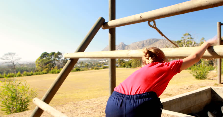 Girl exercising on outdoor equipment during obstacle course in boot camp