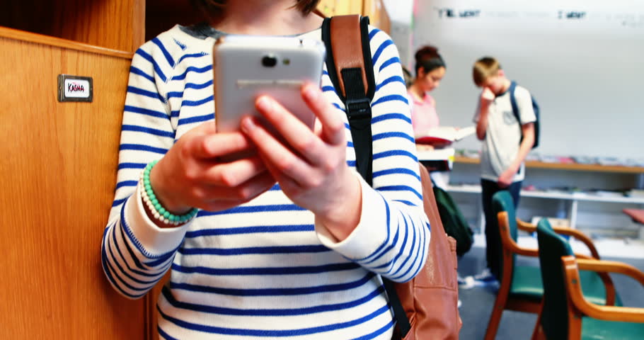 Front view of Caucasian smiling school girl using mobile phone in class room at school
