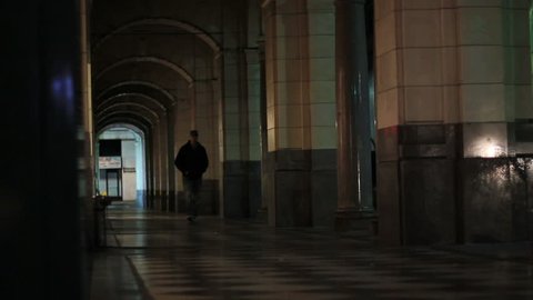 A man walks down a dark arched pathway at night alone - Βίντεο στοκ