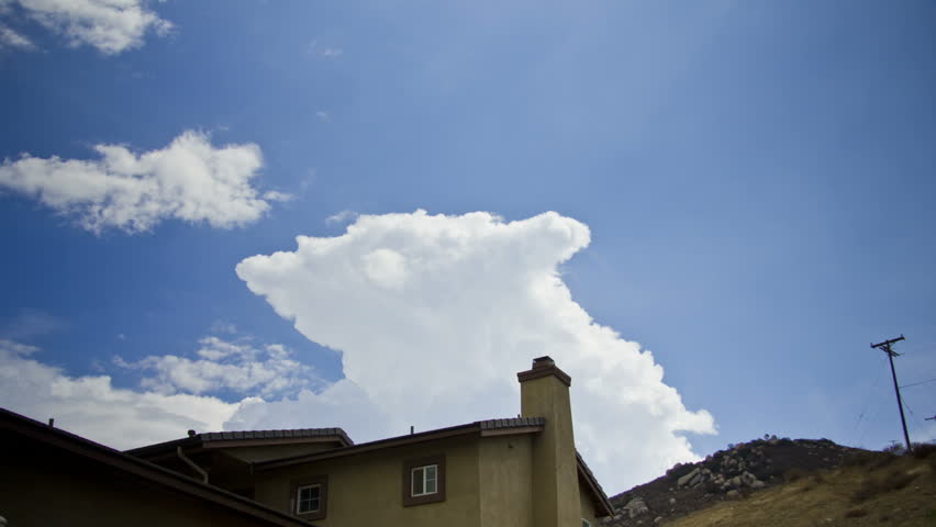 A storm cloud builds in time lapse over a house in the hills. Illustration of a