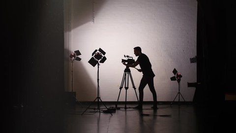 Working Behind the Scenes in Film Studio: Silhouette of Anonymous Cameraman Using Camera 