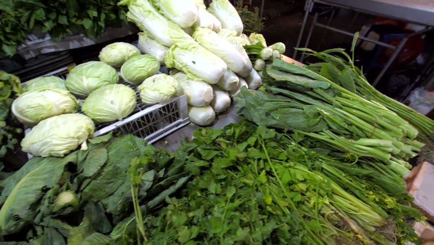Fresh vegetables and herbs at night street market in Phuket, Thailand: cucumbers, cabbage, potato, onion, carrot, courgettes, etc