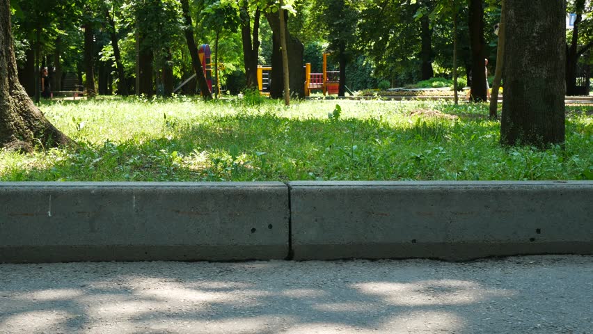 We see only the feet of a girl. A woman in sneakers is walking along the curb.