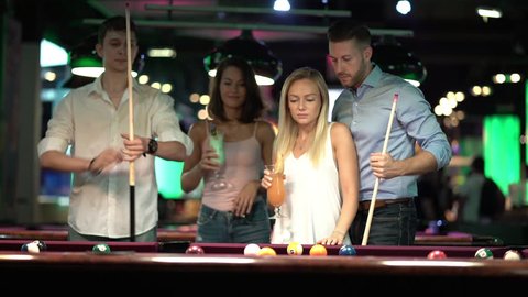 two happy young couples playing billiard together

