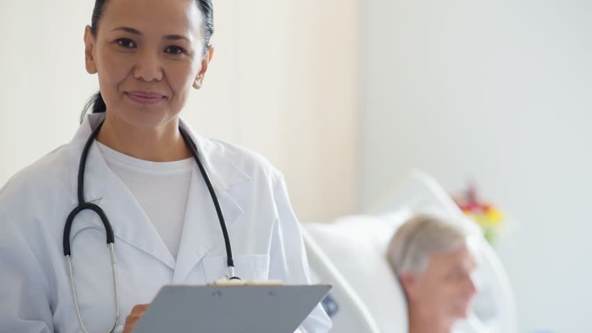 Cheerful adul female doctor standing in the hospital ward