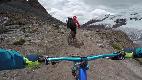 Follow Cam POV Of Male Mountain Biking Through Massive Mountains On Sunny Day