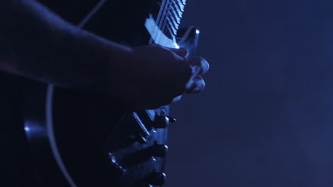 Guitarist rocker with dreadlocks playing the electric guitar on stage. Performance music video rock, punk, heavy metal band.