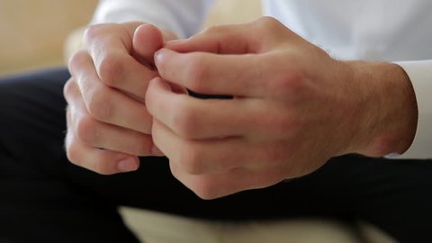 Close up of male hands clenched together in the air, then rubbed, and touching fingers and palms with fingers, concentrating , thinking or making decision, nervous. Male dressed classic fo business or