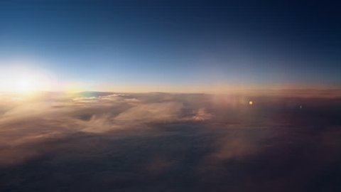 Flying over the evening clouds with the late sun. Flight through moving cloudscape with beautiful sun rays. Traveling by air through an airplane window. Perfect for cinema, background
