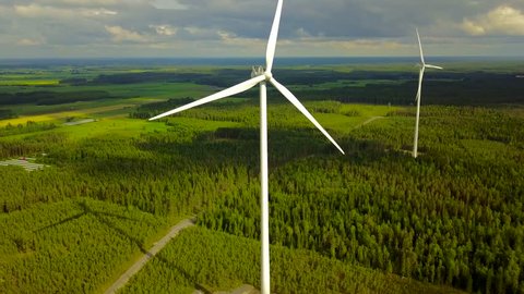 Wind turbines on forest on cloudy day, 4K aerial video. 