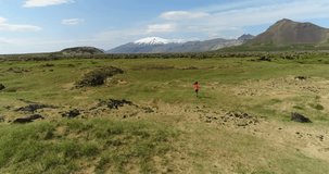 Aerial drone footage Iceland landscape with tourist woman running having fun by West Iceland famous snaefellsjokull volcano mountain on Snaefellsnes peninsula.