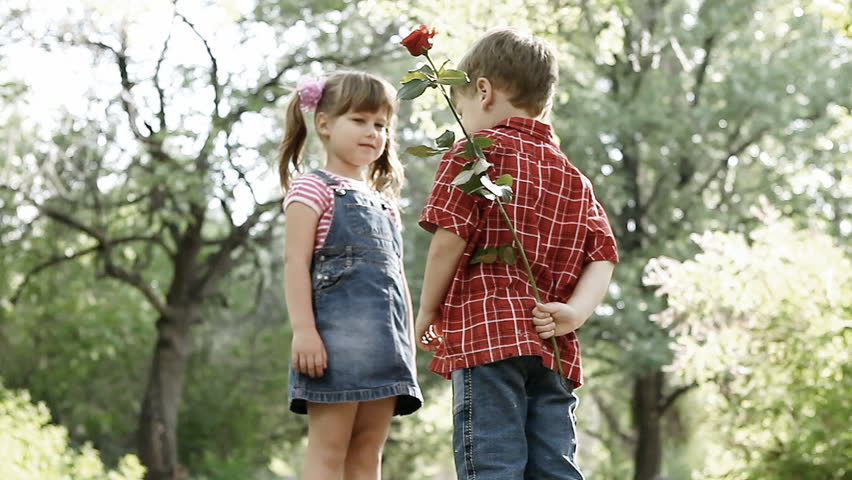 Two children speaking and boy presents flower