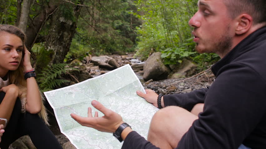 Tourists study the map of the area in a camping near the creek