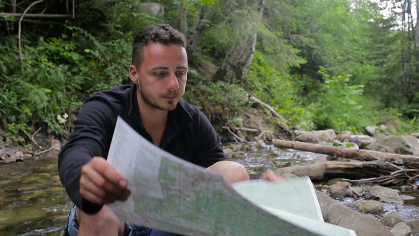 Hikers with a map in a camping near the creek