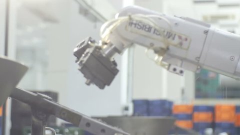 KAZAN, TATARSTAN/RUSSIA - MAY 11 2016: Side view white modern high-tech Mitsubishi robotic arm takes and puts metal round details on conveyor on May 11 in KAZAN