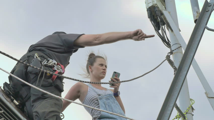 Professional climber with woman near the network tower at the roof
