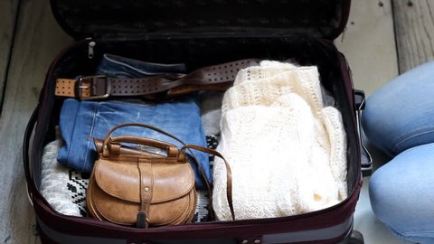 A young woman puts things in a suitcase. The concept of travel and trip
