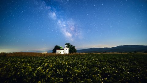 Timelapse of the night sky with stars and milky way over a small building during summer time.