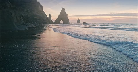 AERIAL: flying rocky coastline, three sisters & elephant rock at sunset in Taranaki, New Zealand