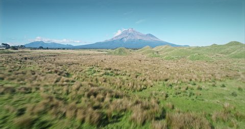 AERIAL: flying over farm and volcanic hill mounds looking out to Mt Taranaki / Mt Egmont, New Zealand