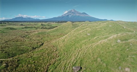 AERIAL: flying over farm and volcanic hill mounds looking out to Mt Taranaki / Mt Egmont, New Zealand